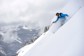 A man surrounded by snow powder skiing down a mountain in Colorado.